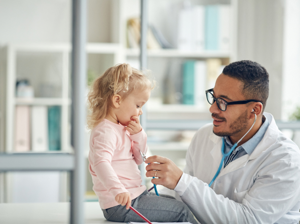 Physician with a stethoscope to a young girls chest listening to hear heartbeat during a routine check-up