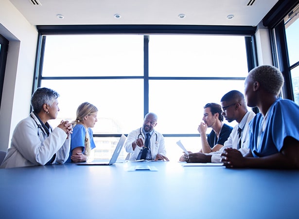 A diverse team of medical professionals during a meeting around a conference table in a hospital